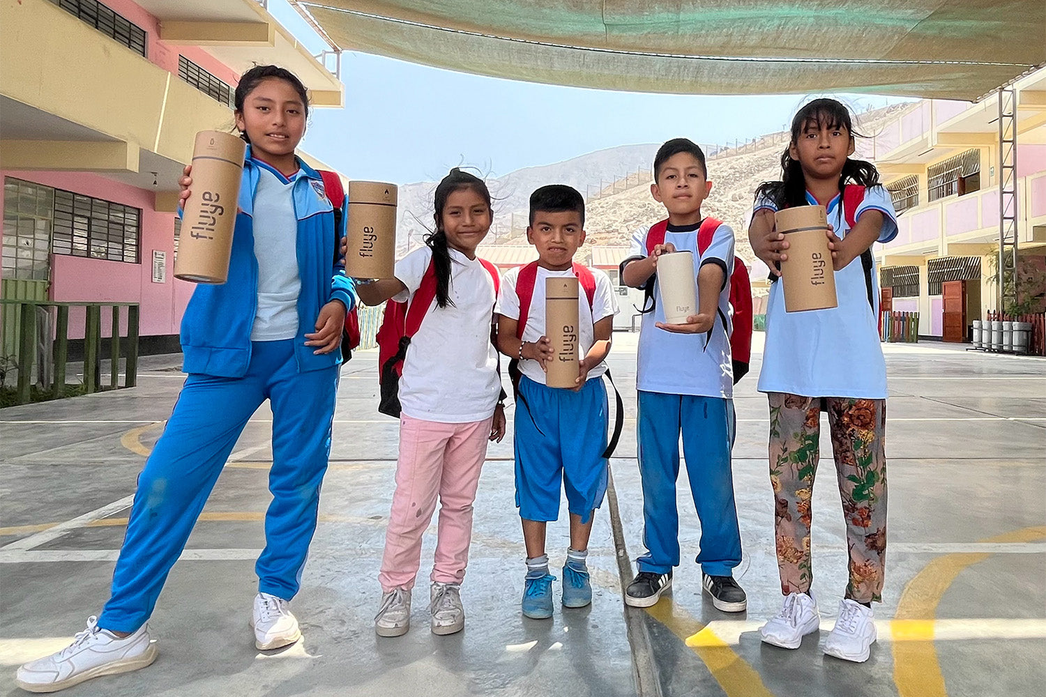 Image of Un grupo de niños escolares muestra cada uno un envase de Fluye.