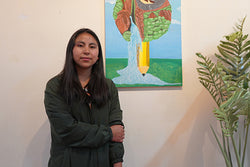 Image of Una mujer sonríe frente a un cuadro pintado. 